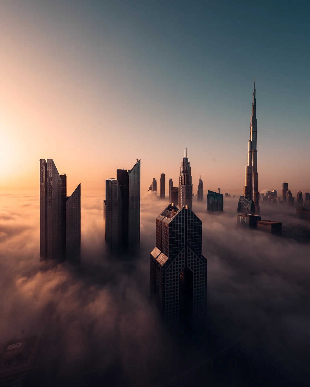 Dubai skyscrapers rising above low cloud at sunrise