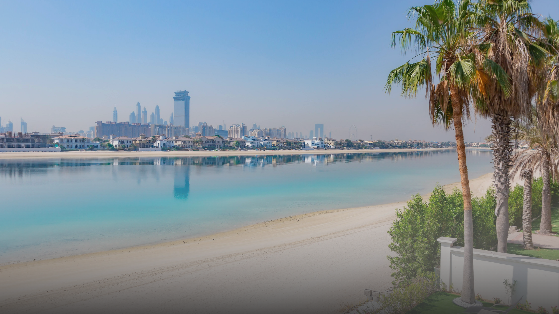 Palm-lined beach with the Dubai skyline across the water
