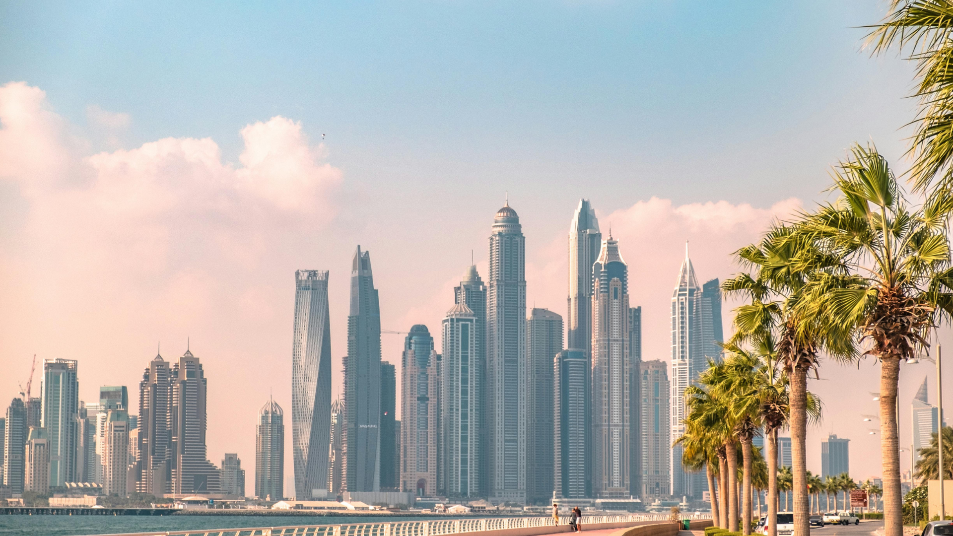 Dubai Marina towers seen past palm trees at dusk